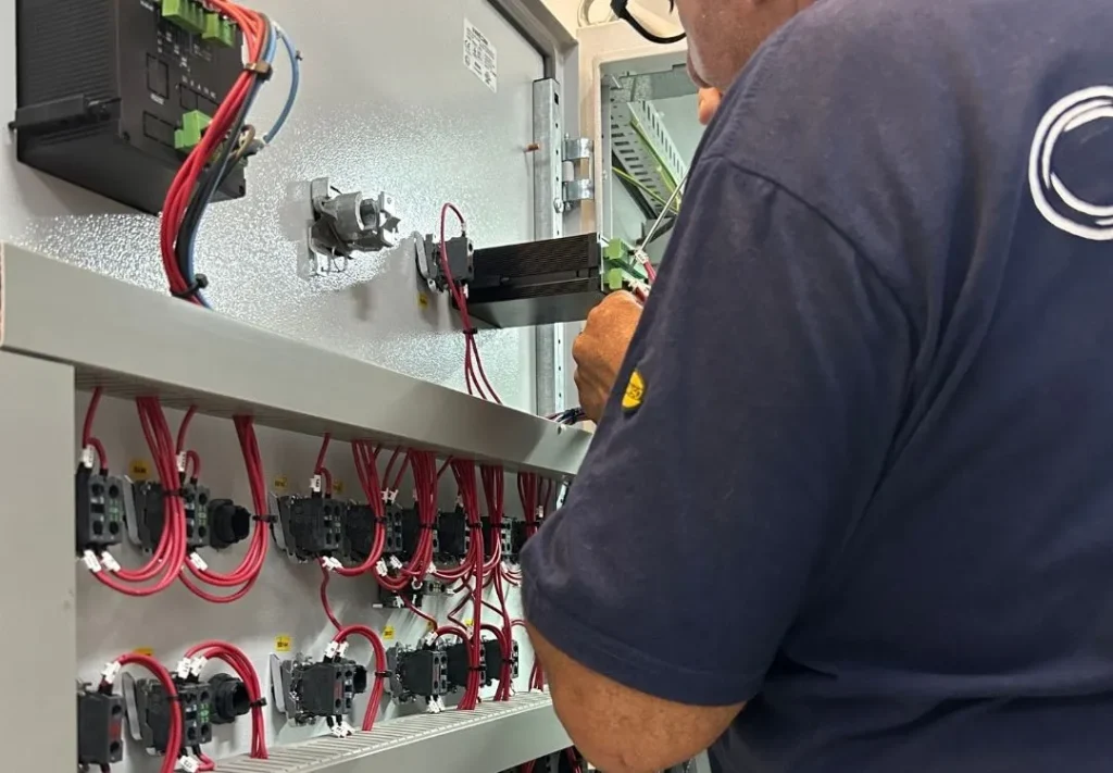 Técnico de C+D cableando un tablero eléctrico industrial en el taller